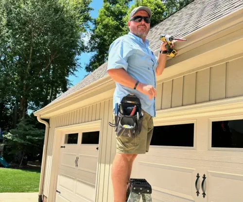 Mike Burroughs, owner of Burroughs Roofing, standing on a ladder inspecting the roof of a home.