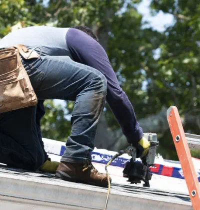 A worker installs new shingles to repair a damaged roof