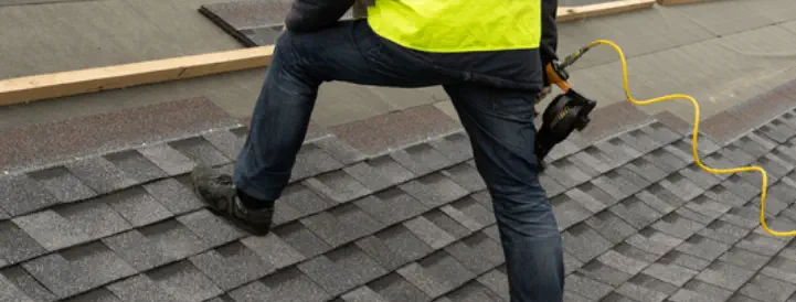 A roofing contractor installs new shingles on a residential roof